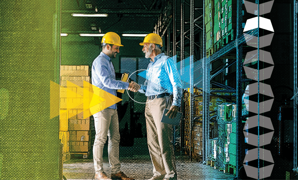 two men shaking hands in front of boxes in warehouse, representing finding a good manufacturing 3PL provider