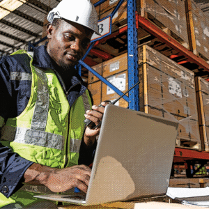 Warehouse worker in warehouse with laptop, representing the importance of a transition framework and team alignment when starting with a new manufacturing 3PL