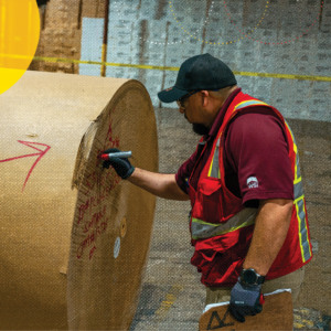 Railcar loading and unloading warehouse operator inspecting the paper roll from a loaded railcar.