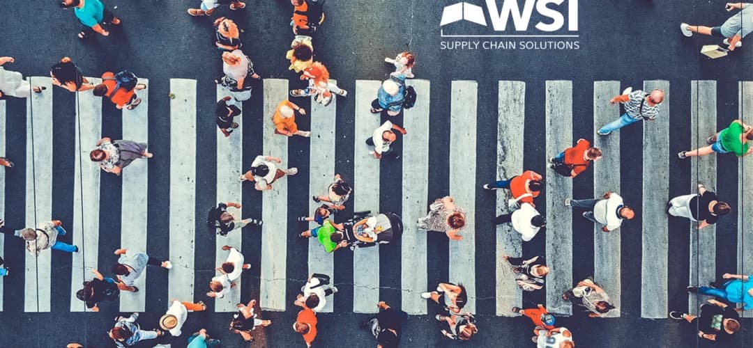 People crossing road on busy crosswalk with WSI logo