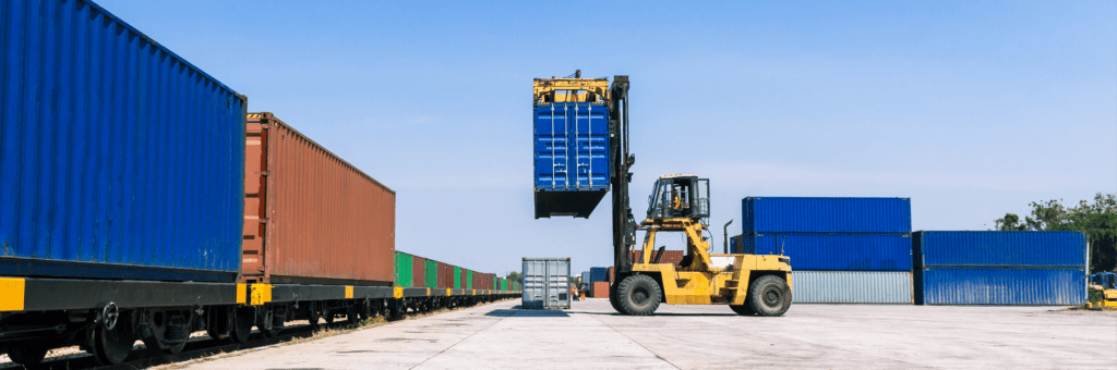 forklift moving shipping containers in a lot