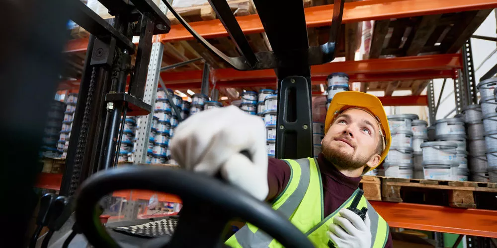 warehouse worker driving forklift to move pallets