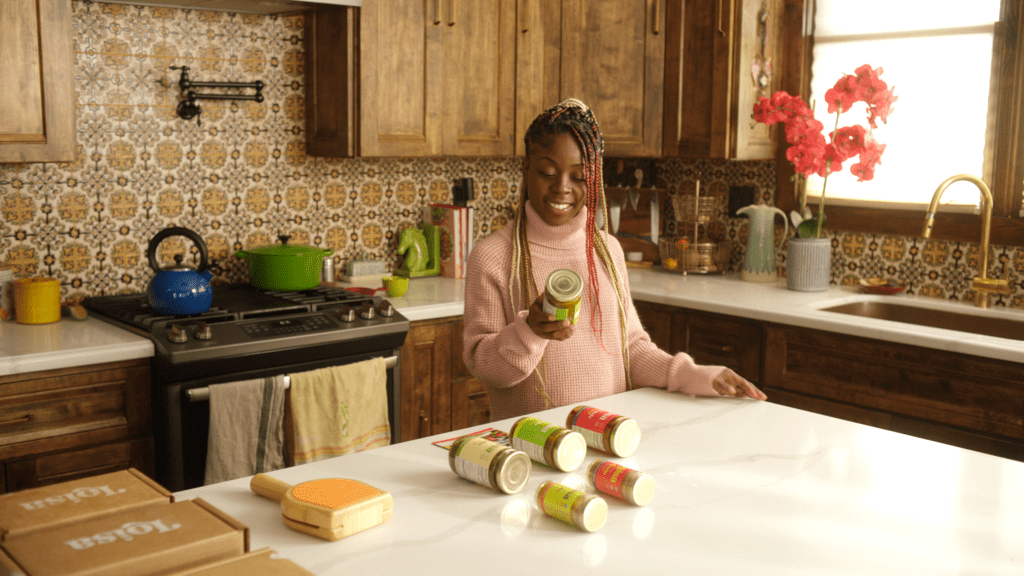 smiling woman standing at kitchen counter looking at loisa jar label