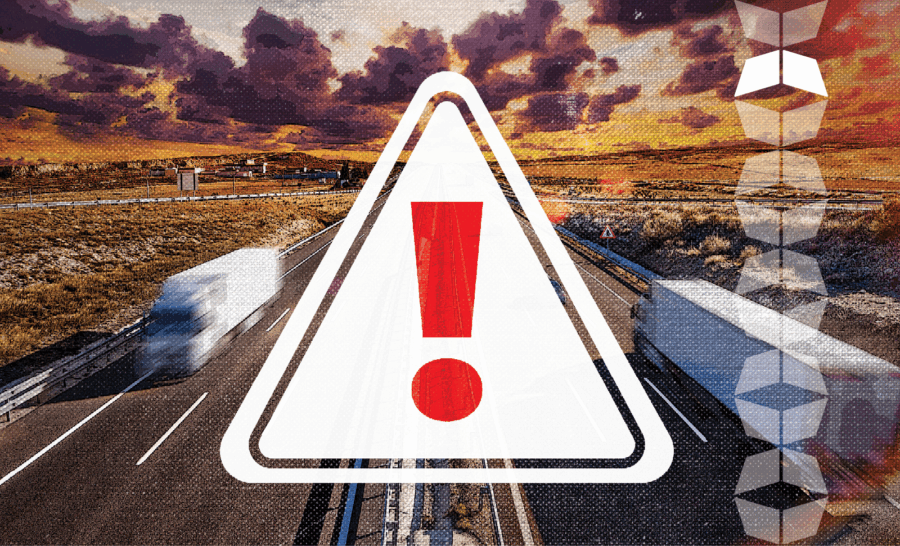 trucks on highway with sign with exclamation point overlay, reflecting the rising threat of freight fraud