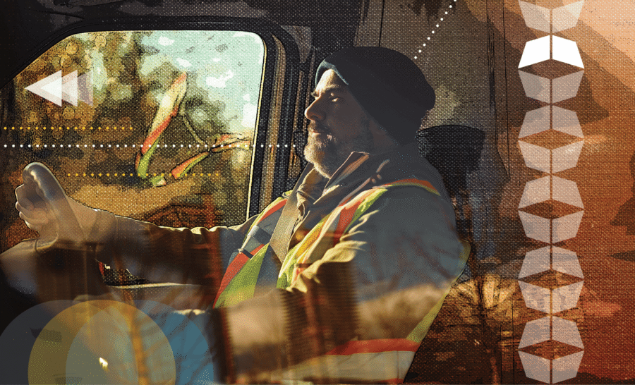 Truck driver wearing a safety vest in a cab, illustrating how non-domiciled CDL rules affect industrial freight capacity.